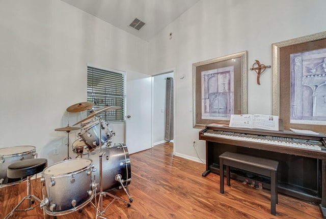 misc room with high vaulted ceiling and wood-type flooring