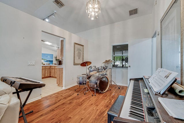 interior space with rail lighting, an inviting chandelier, and light hardwood / wood-style flooring