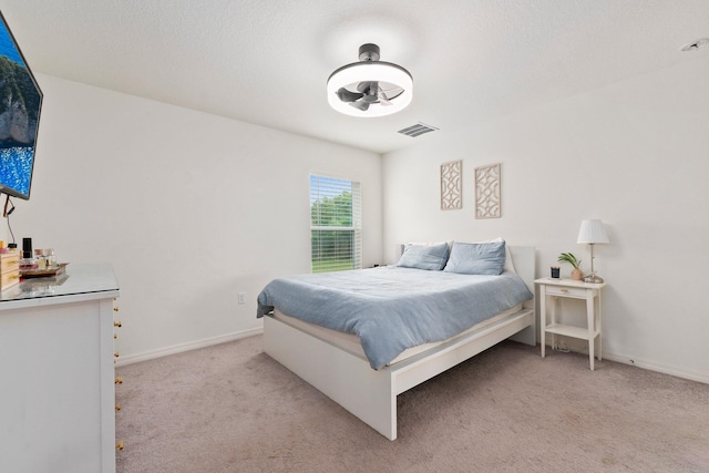 bedroom with a textured ceiling and light colored carpet