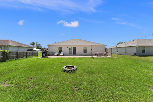 rear view of property with a fire pit, a patio, and a yard