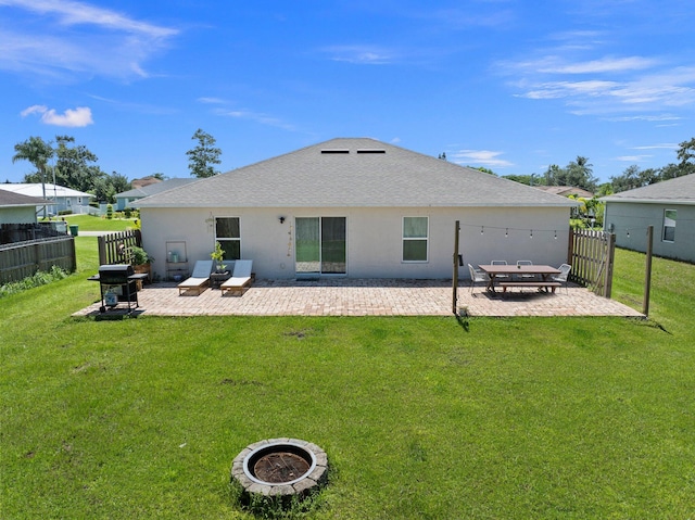 rear view of house featuring a patio, an outdoor fire pit, and a yard