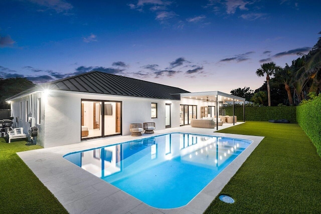 back house at dusk with a patio, french doors, a fenced in pool, a yard, and outdoor lounge area