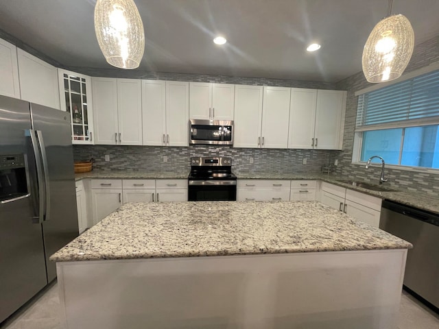 kitchen with white cabinets, decorative light fixtures, a center island, and stainless steel appliances