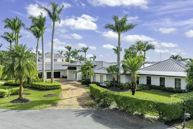 view of front of house featuring a front yard, a standing seam roof, metal roof, and stucco siding