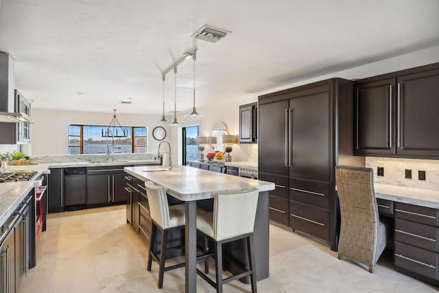 kitchen featuring light countertops, pendant lighting, a kitchen island with sink, and visible vents