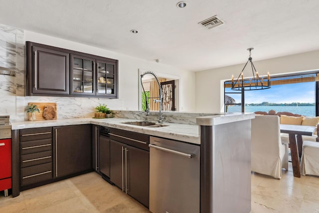 kitchen with dark brown cabinetry, a water view, visible vents, hanging light fixtures, and glass insert cabinets