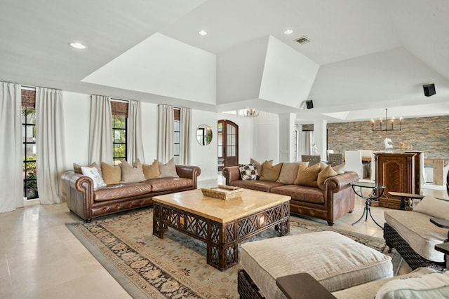 living room featuring ornate columns, a high ceiling, and an inviting chandelier