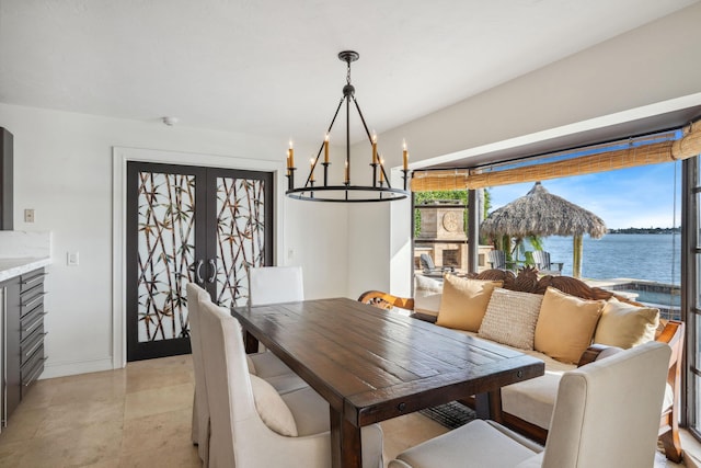 dining area featuring a water view, an inviting chandelier, baseboards, and french doors