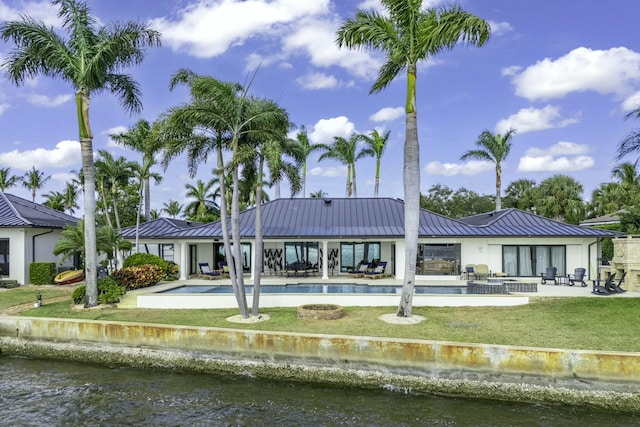 back of house featuring a patio, a water view, and a lawn