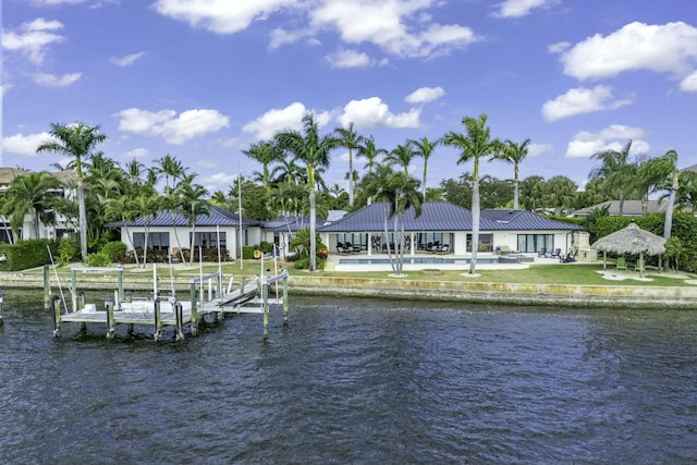 dock area with a yard, a water view, boat lift, and a pool