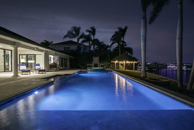 view of pool featuring a pool with connected hot tub, a water view, and a patio