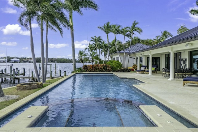 view of swimming pool with a patio, a boat dock, a water view, and a pool with connected hot tub