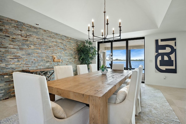 dining room featuring a water view, baseboards, and a chandelier