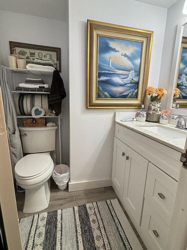 bathroom with hardwood / wood-style floors, toilet, and vanity