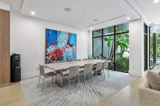 dining area with light wood finished floors, a wall of windows, and baseboards