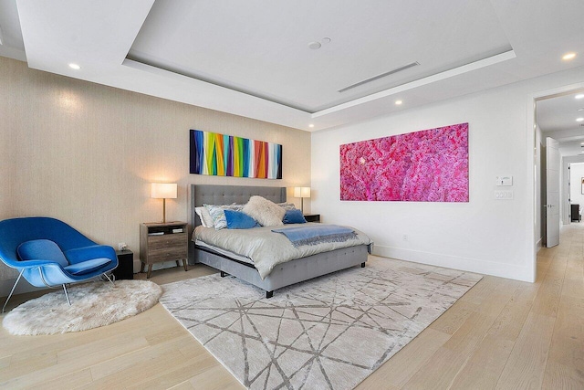 bedroom featuring baseboards, visible vents, wood finished floors, a tray ceiling, and recessed lighting