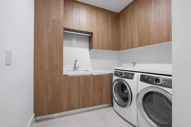 clothes washing area with a sink, light tile patterned floors, washing machine and clothes dryer, and cabinet space