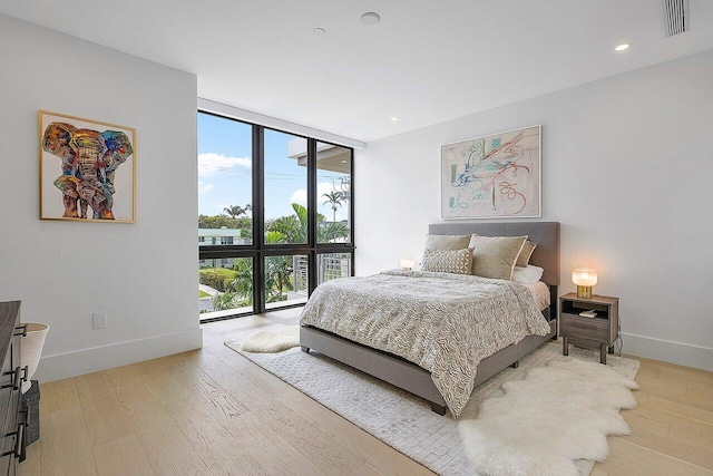 bedroom featuring recessed lighting, visible vents, wood finished floors, a wall of windows, and baseboards