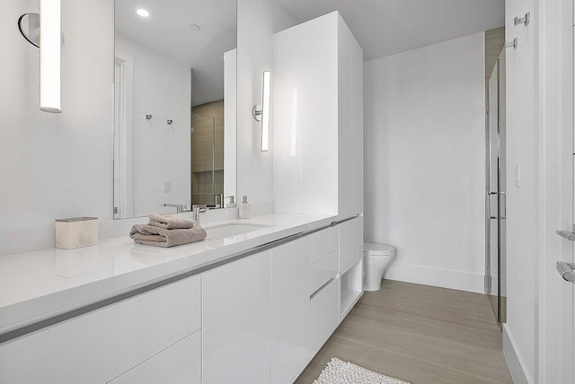 full bath with a stall shower, vanity, toilet, and baseboards