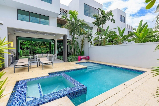 view of swimming pool with a patio, outdoor dining space, fence, and a pool with connected hot tub