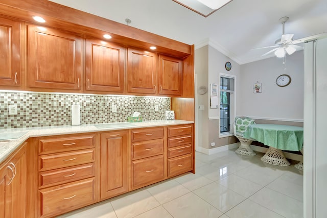 kitchen with decorative backsplash, light tile patterned flooring, vaulted ceiling, ceiling fan, and ornamental molding