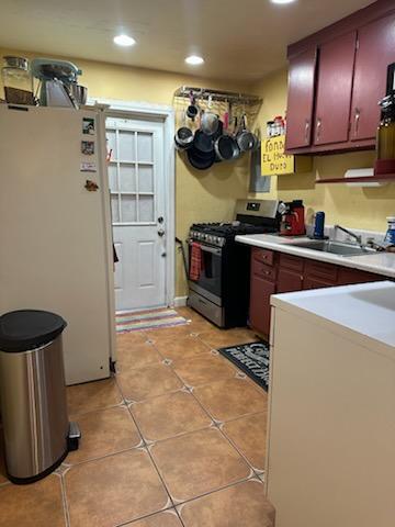 kitchen with sink, white fridge, light tile patterned floors, and gas range