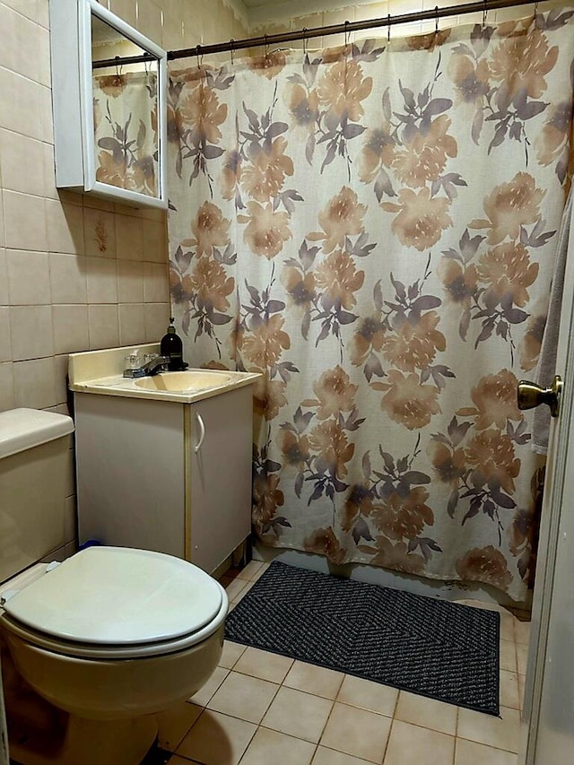 bathroom featuring tile patterned floors, toilet, vanity, curtained shower, and tile walls