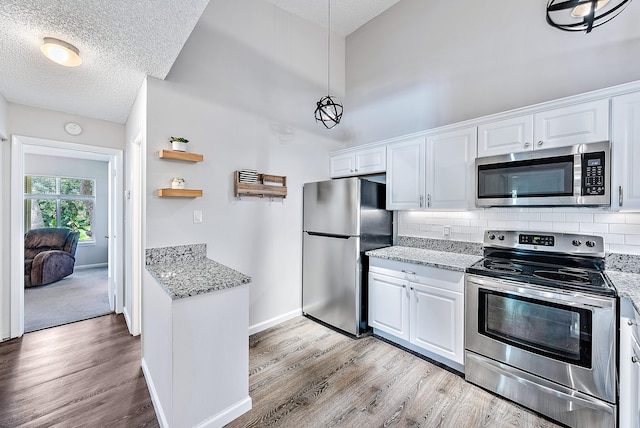 kitchen featuring appliances with stainless steel finishes, white cabinetry, and light hardwood / wood-style floors