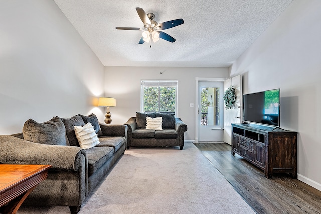 living room with dark wood-type flooring, a textured ceiling, and ceiling fan