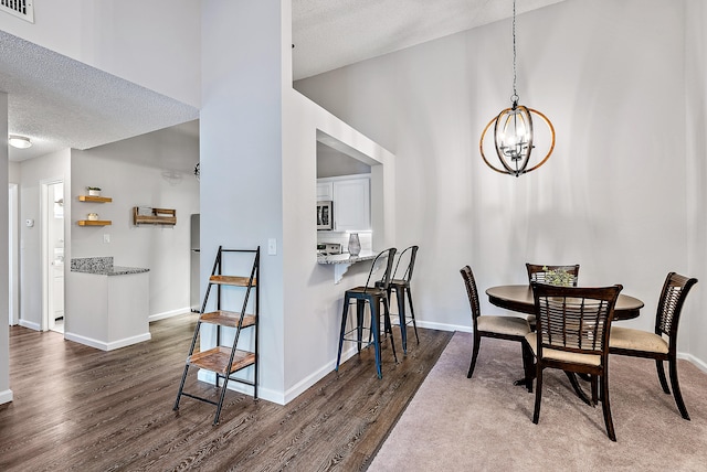 dining area featuring a textured ceiling, an inviting chandelier, a high ceiling, and dark hardwood / wood-style floors