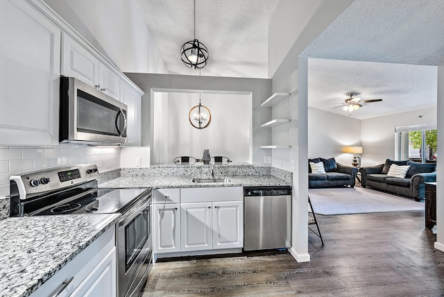 kitchen with ceiling fan with notable chandelier, appliances with stainless steel finishes, dark wood-type flooring, and white cabinets