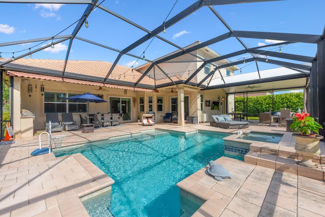 view of swimming pool featuring an in ground hot tub, glass enclosure, ceiling fan, and a patio area