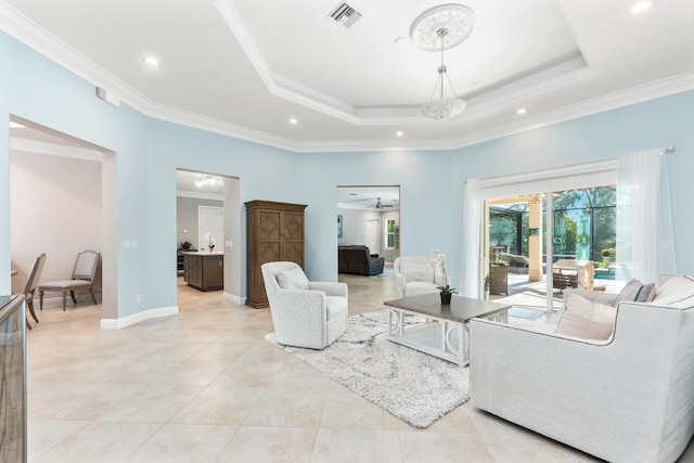 living room featuring ceiling fan, a tray ceiling, and ornamental molding