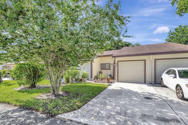 view of front of house with a garage, concrete driveway, a front yard, and stucco siding