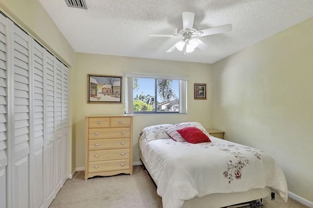 bedroom featuring a ceiling fan, light colored carpet, baseboards, and a textured ceiling