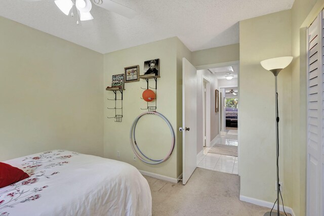 bedroom with baseboards, light colored carpet, a ceiling fan, and a textured ceiling