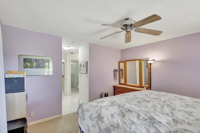 bedroom featuring baseboards, light colored carpet, a textured ceiling, ensuite bath, and a ceiling fan