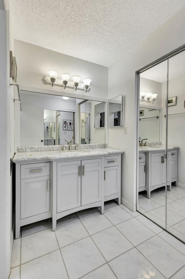 bathroom with a sink, tile patterned floors, two vanities, and a textured ceiling