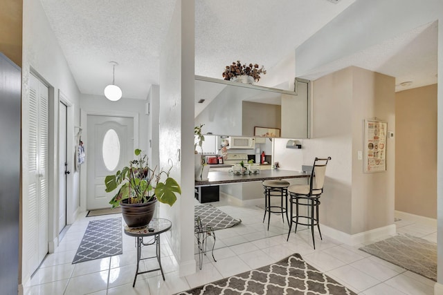 foyer entrance with light tile patterned floors, baseboards, and a textured ceiling