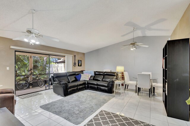 living room with vaulted ceiling, light tile patterned floors, a ceiling fan, and a textured ceiling