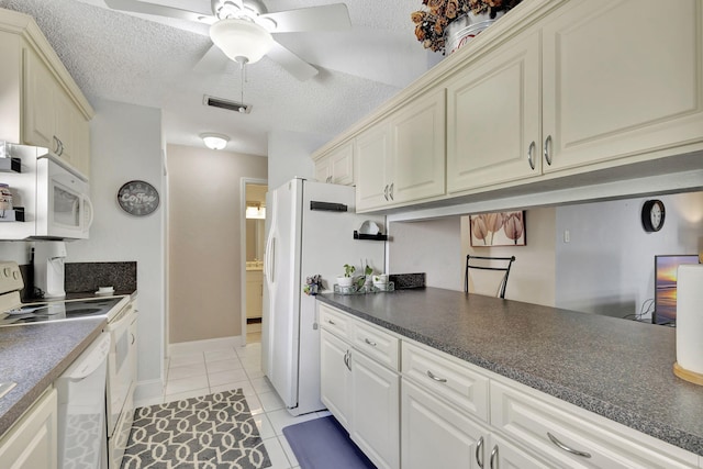 kitchen with visible vents, white appliances, dark countertops, and a textured ceiling