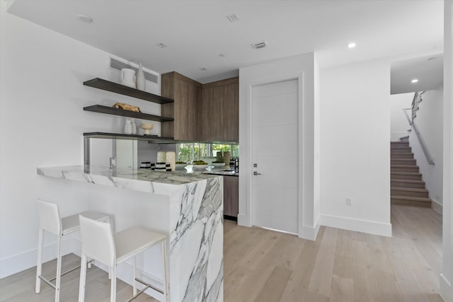 kitchen featuring a breakfast bar area, kitchen peninsula, and light hardwood / wood-style floors