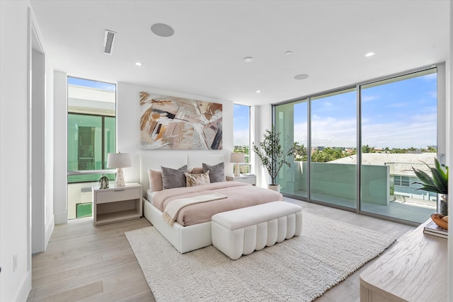 bedroom with light hardwood / wood-style floors, floor to ceiling windows, and access to outside