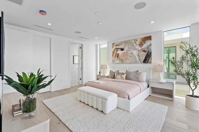 bedroom with a wall of windows and light wood-type flooring