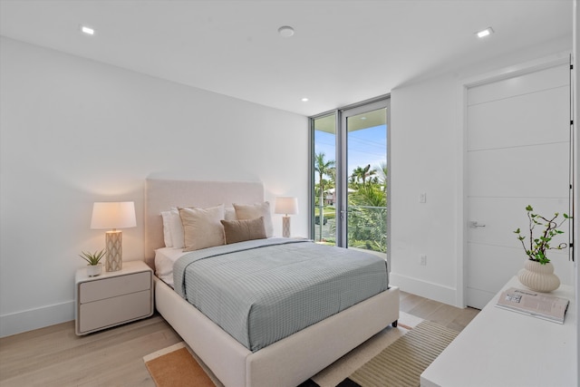 bedroom with multiple windows, light hardwood / wood-style flooring, and expansive windows