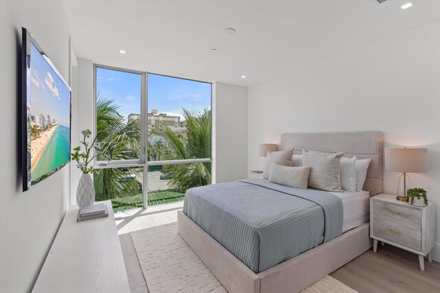 bedroom featuring expansive windows and light hardwood / wood-style floors