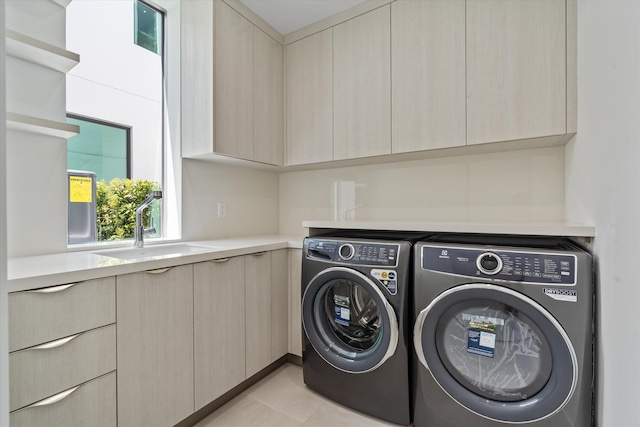 laundry room with washing machine and clothes dryer, sink, light tile patterned flooring, and cabinets