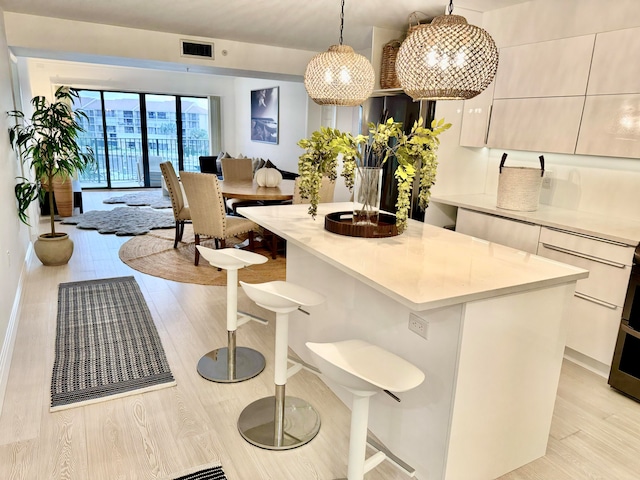 kitchen featuring light hardwood / wood-style flooring, a center island, decorative light fixtures, and a kitchen bar