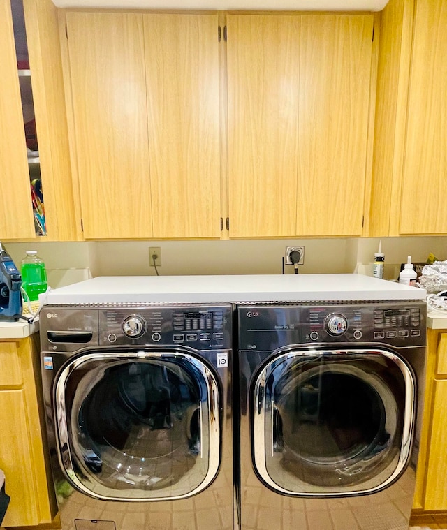 clothes washing area with washer and dryer and cabinets