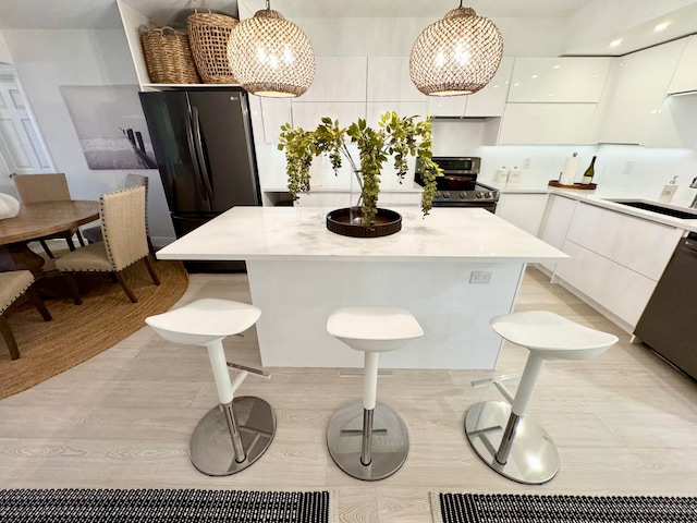 kitchen featuring a kitchen island, white cabinets, hanging light fixtures, and stainless steel electric range oven